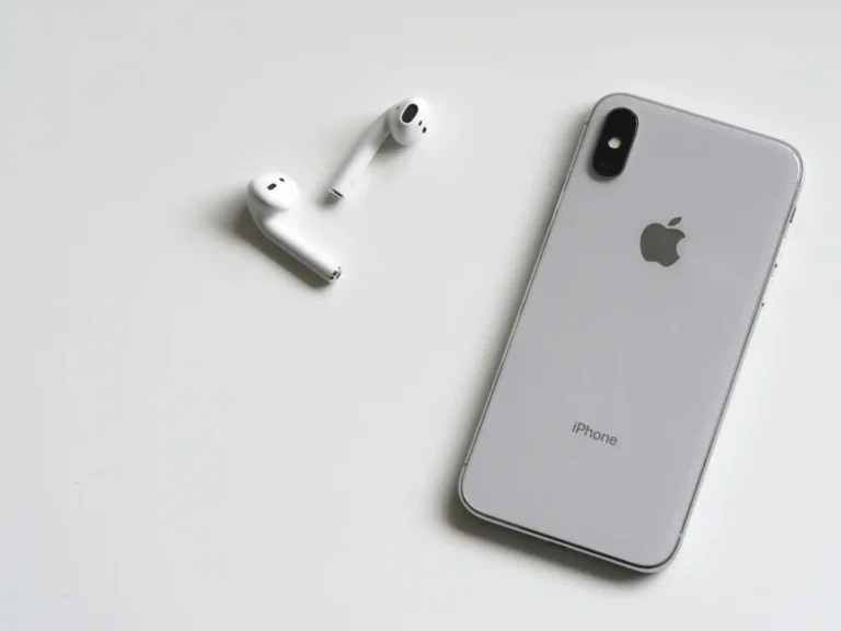 iPhone prateado com AirPods sobre fundo branco